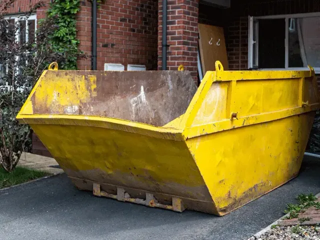 Yellow skip outside a brick house