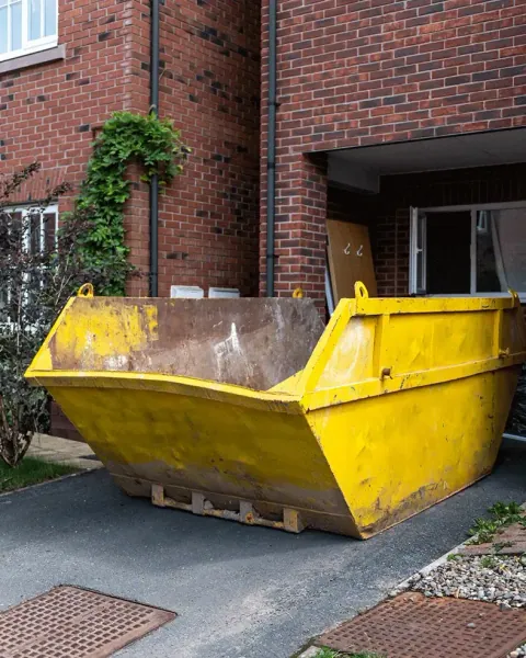 Yellow skip outside a brick house
